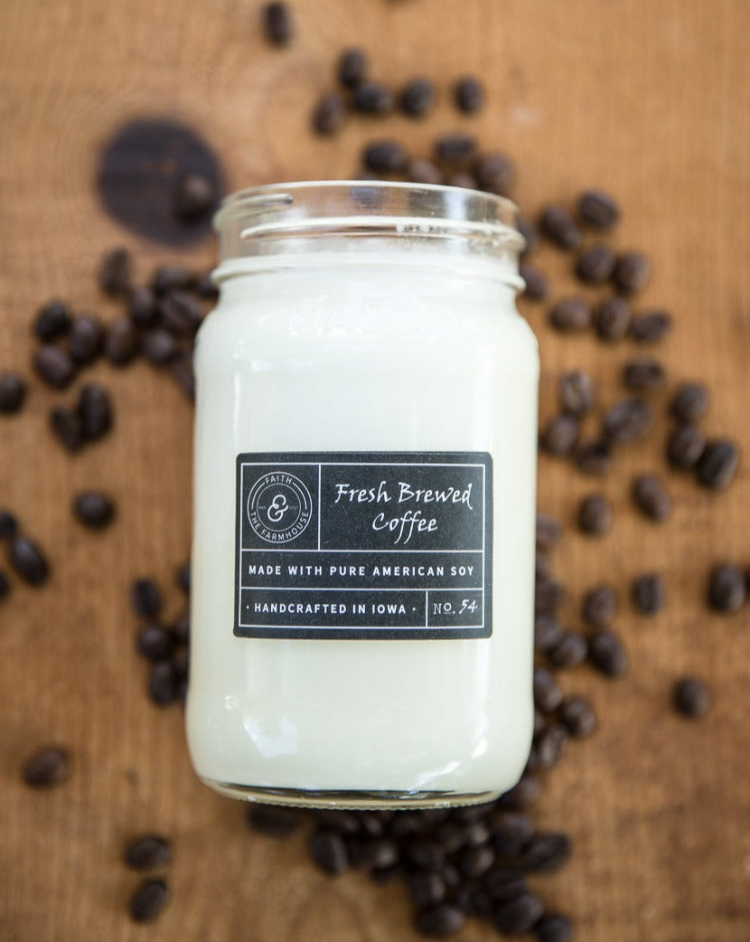 Fresh Brewed Coffee scented candle laying on coffee beans